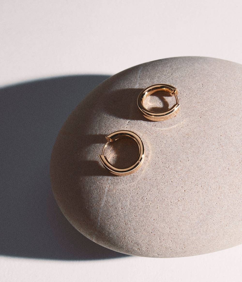 Rose gold liquid earrings on a grey round stone.
