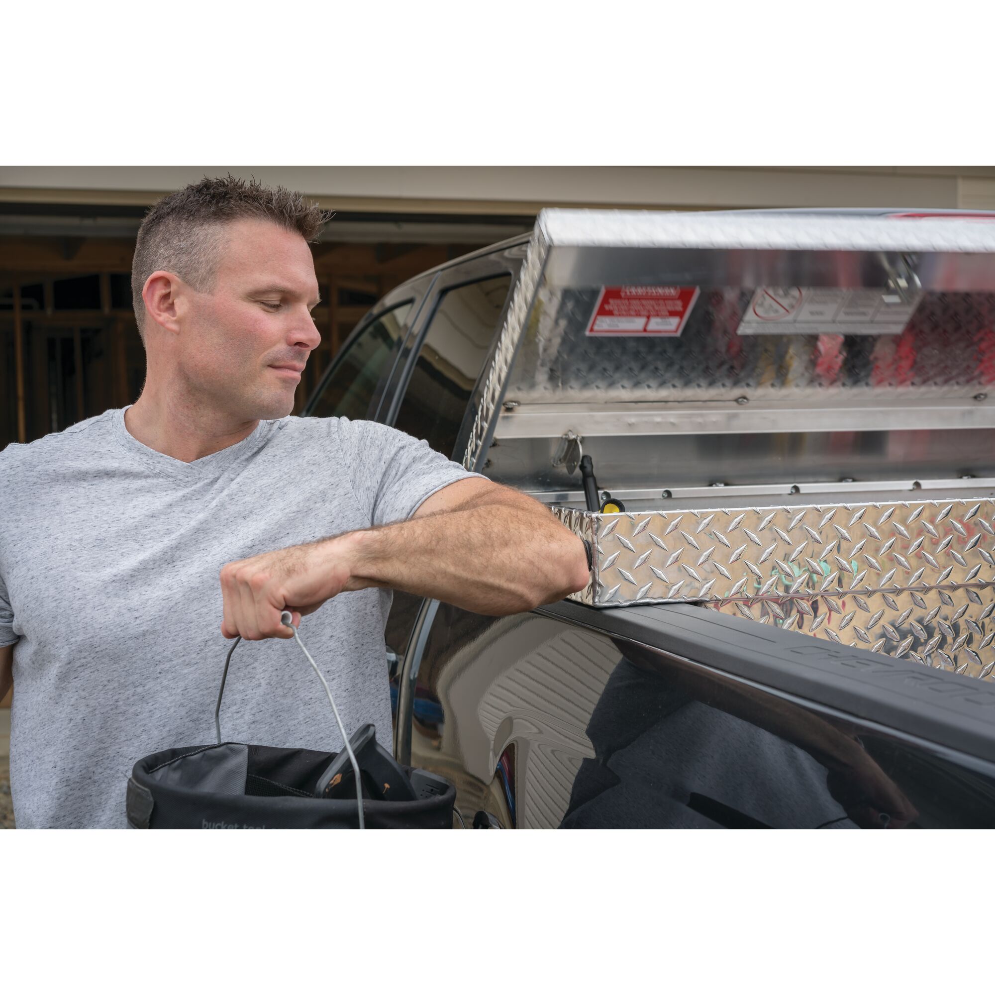 Man unloading a bucket from the back of his pickup truck