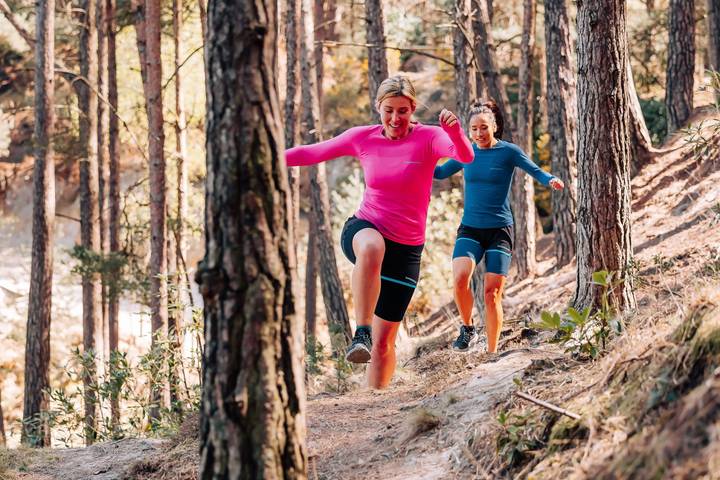 2 Women Running Through Woods Wearing Runderwear Base Layers in Pink and Blue