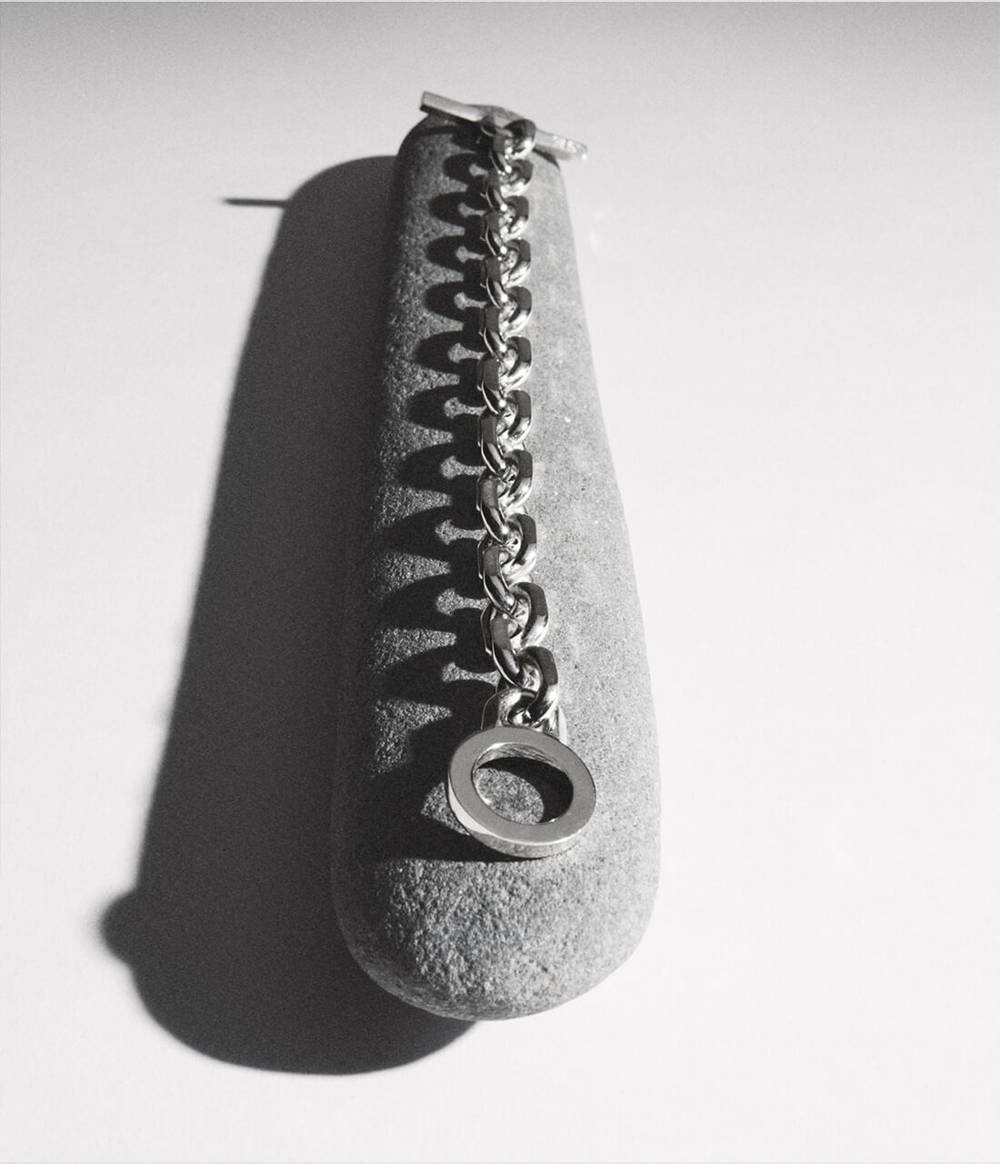 A black and white photo of the Knife Edge silver bracelet is shown on a long stone.