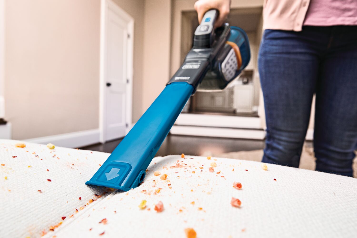 Woman using BLACK+DECKER handheld vacuum on leather couch