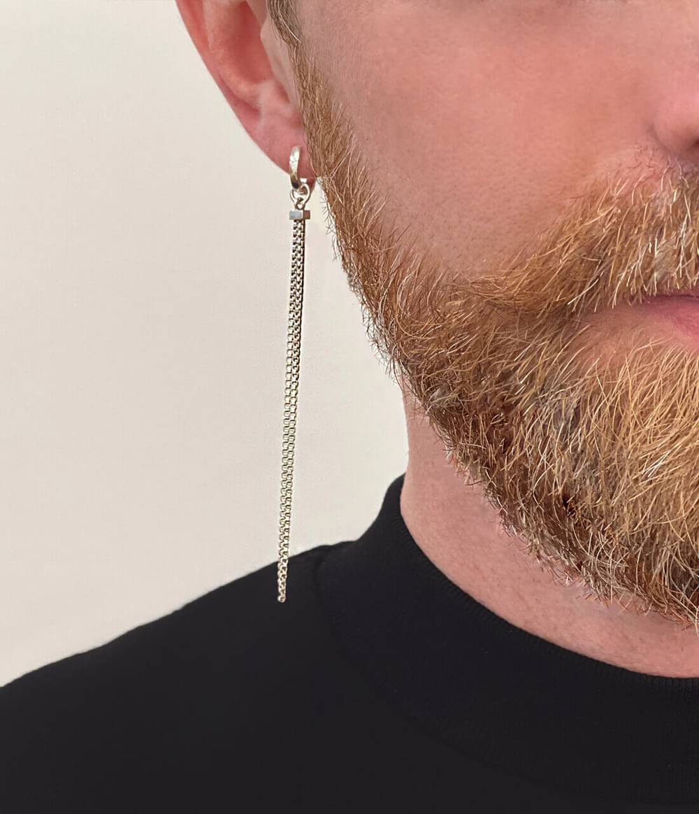 Man in black top and ginger beard is wearing a shimmer long earring attached on a small silver hoop