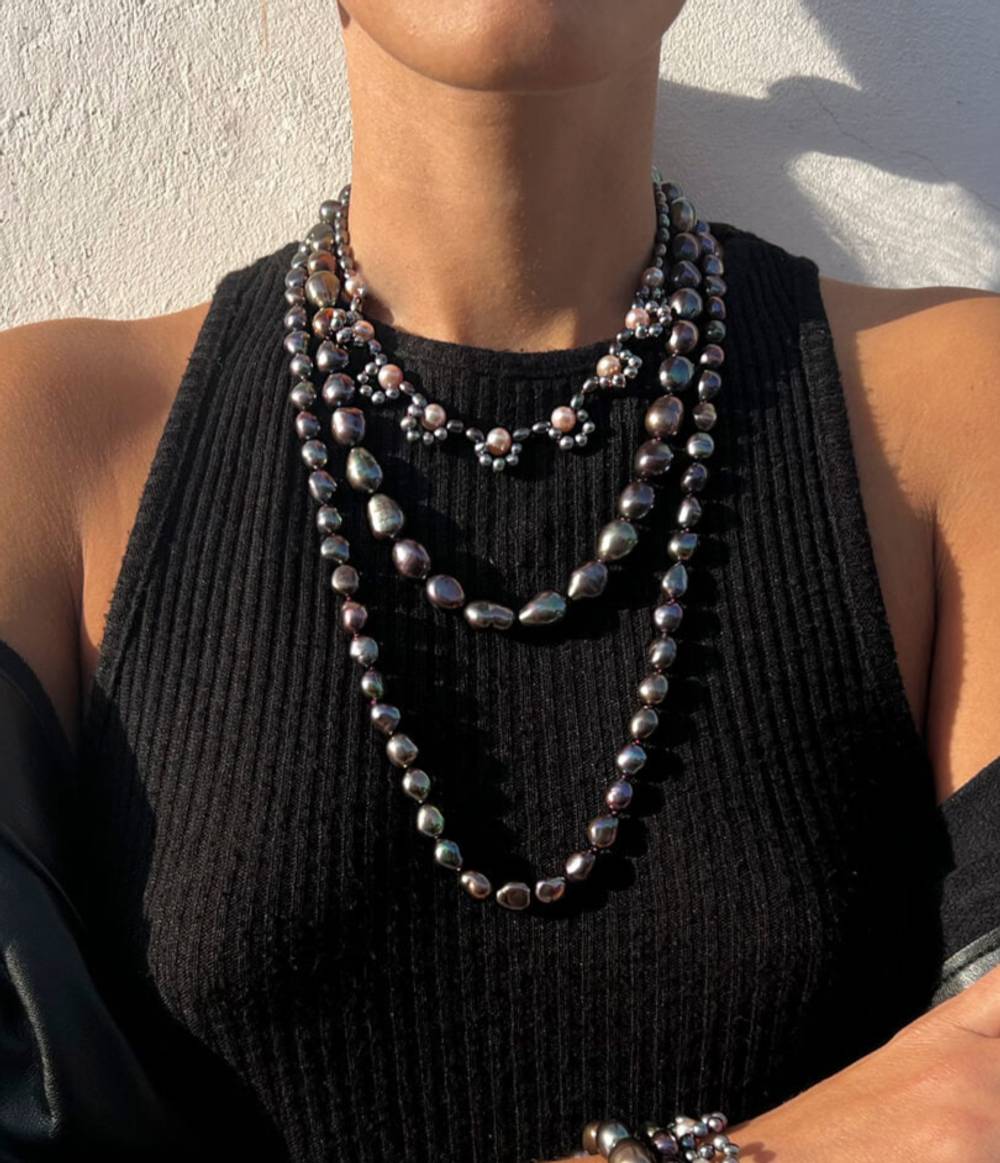 A girl wearing a peacock and pink pearl triple strand necklace from the Coco collection.