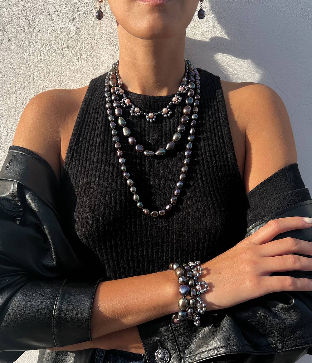 A girl wearing a peacock and pink pearl triple strand necklace and bracelet from the Coco collection.