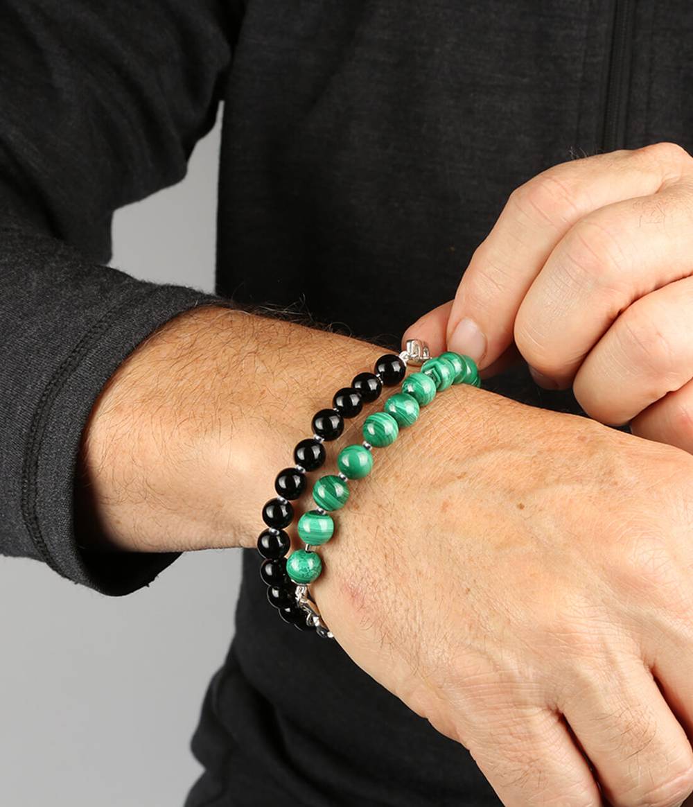 Man wearing two trust bracelets one with malachite and one onyx and silver bids in between.