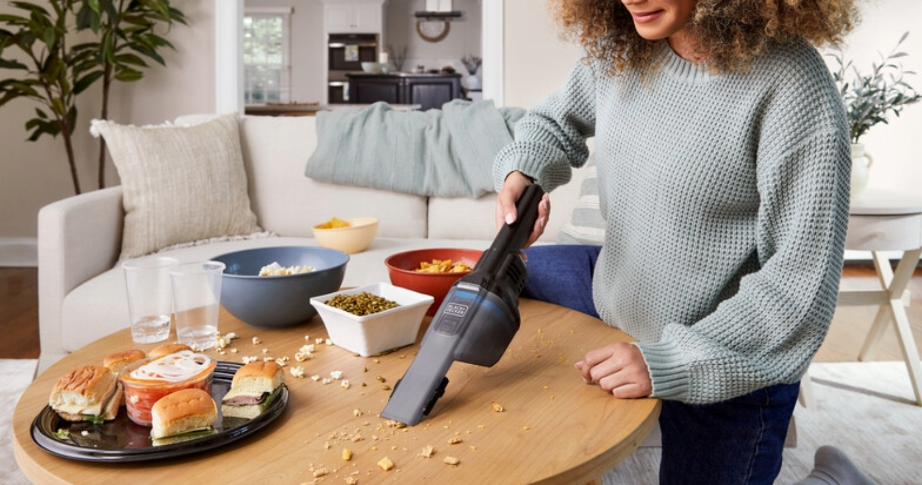 Woman using dustbuster on table on crumbs