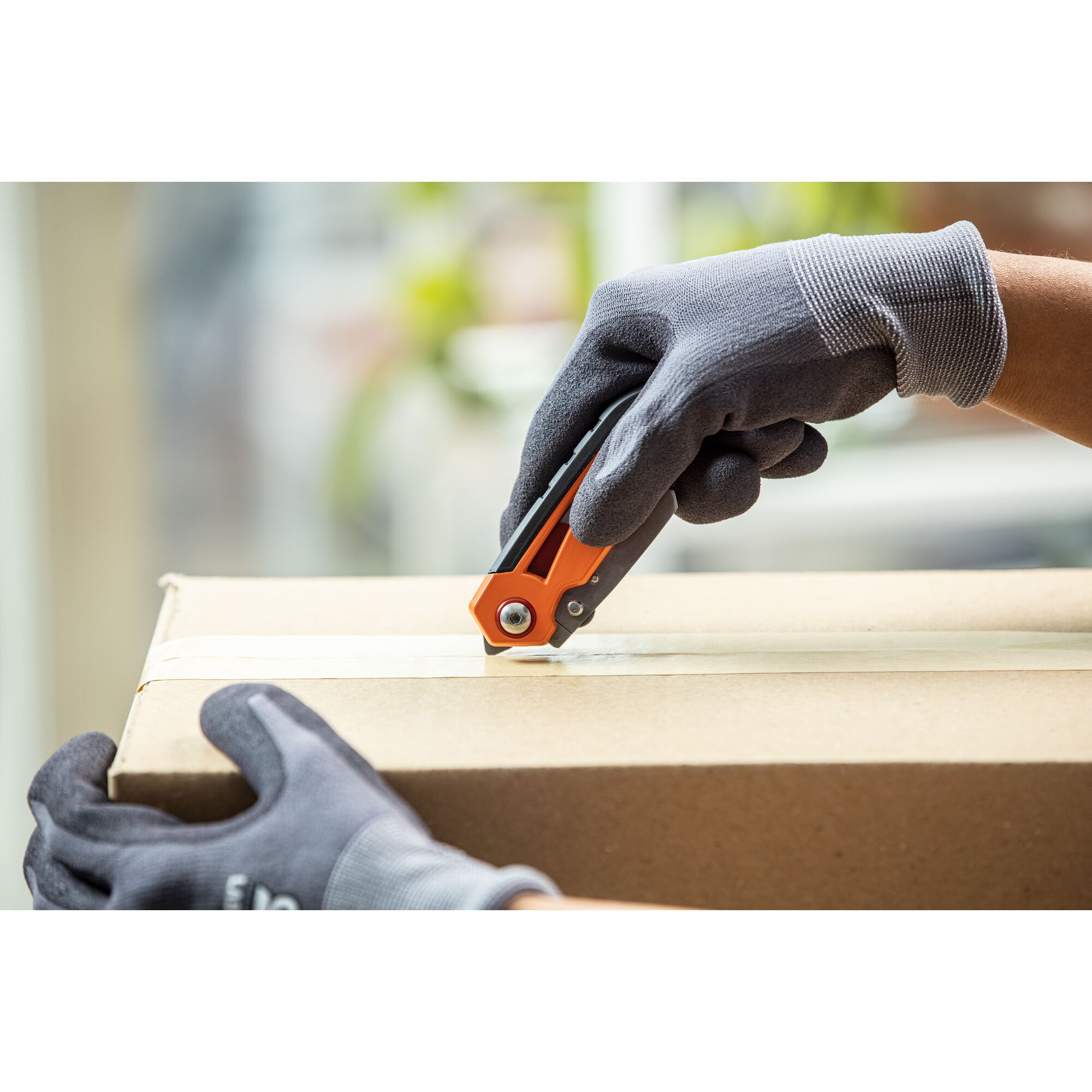 Person using a utility knife on a carboard box