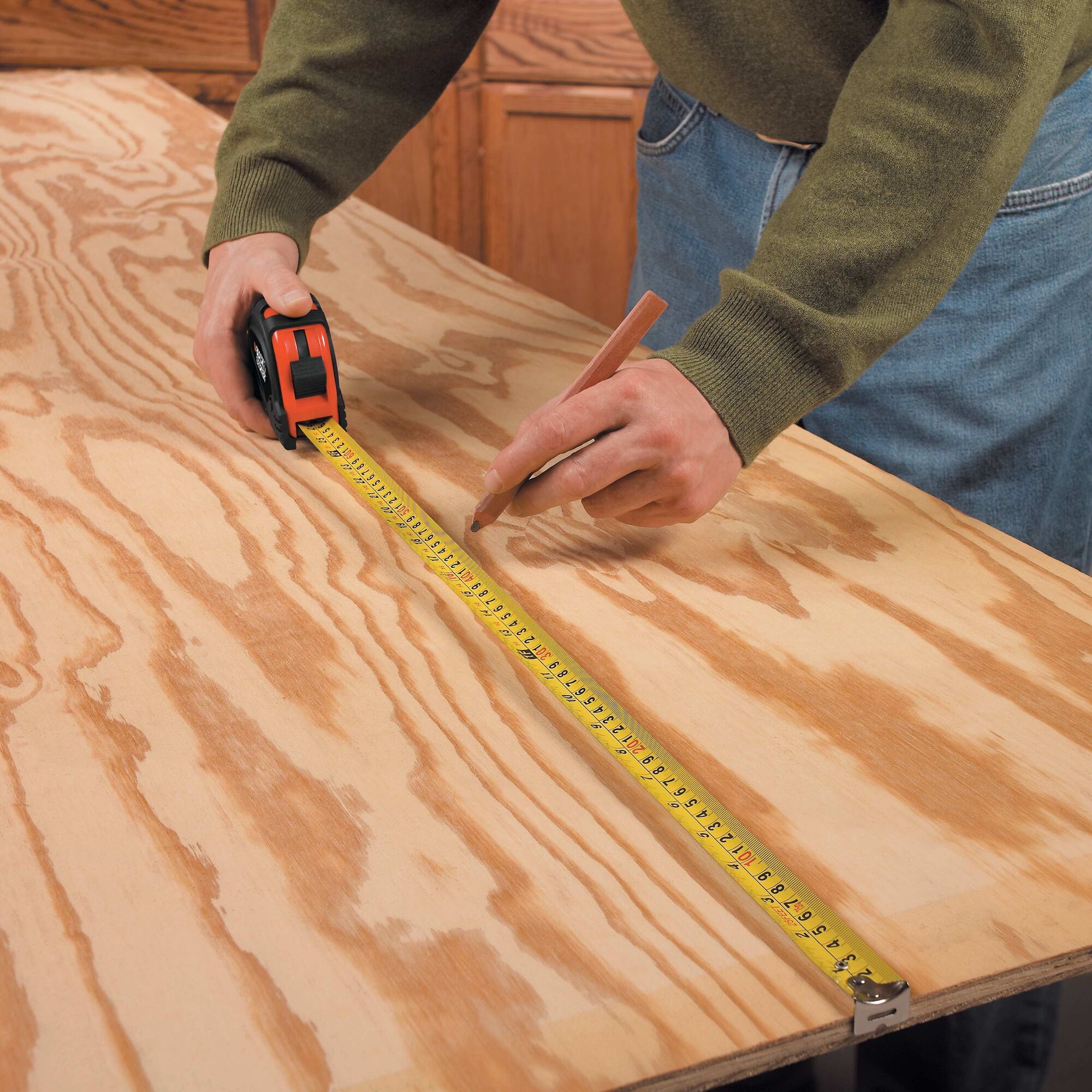 Man using tape measure on wood