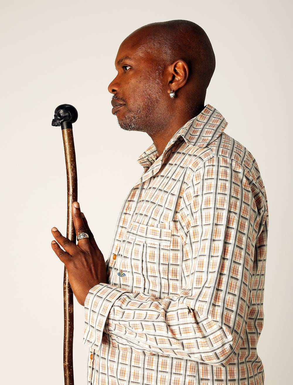 A man is holding a wooden designer's walking stick with a black skull handle.