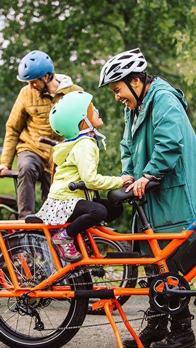 Woman and child in bike helmets smiling at each other while next to an electric bike
