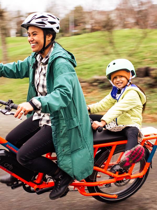 Woman and child in helmets riding an electric cargo bike