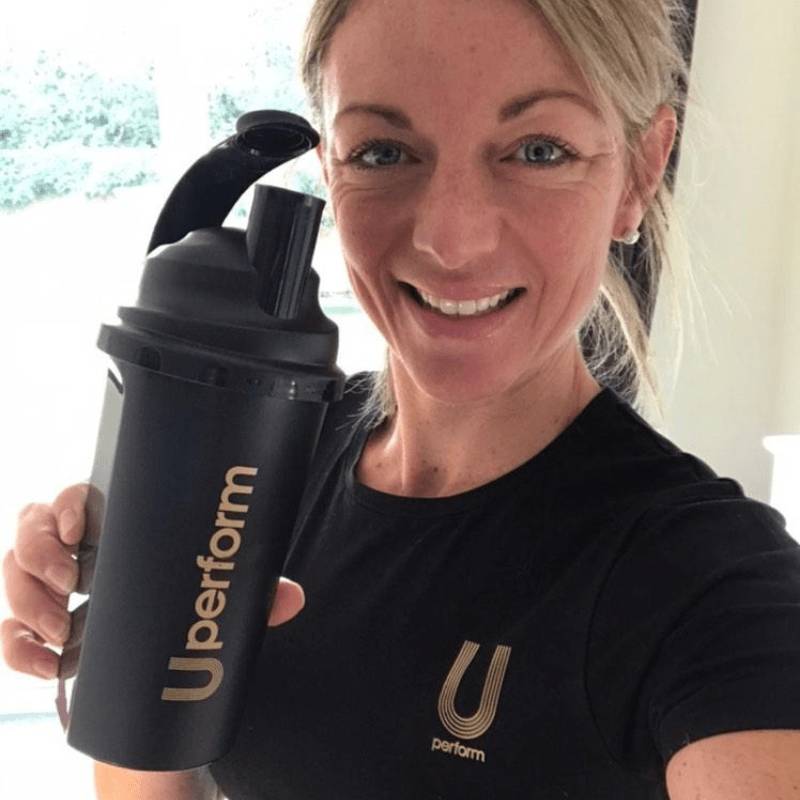 woman holding black and gold U Perform Shaker Bottle wearing black and gold U Perform Active T Shirt