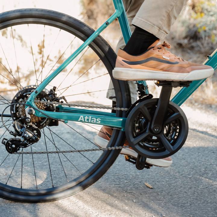 Close-up of a teal bicycle's rear wheel and drivetrain with a focus on the chain and gears, labeled "Atlas."