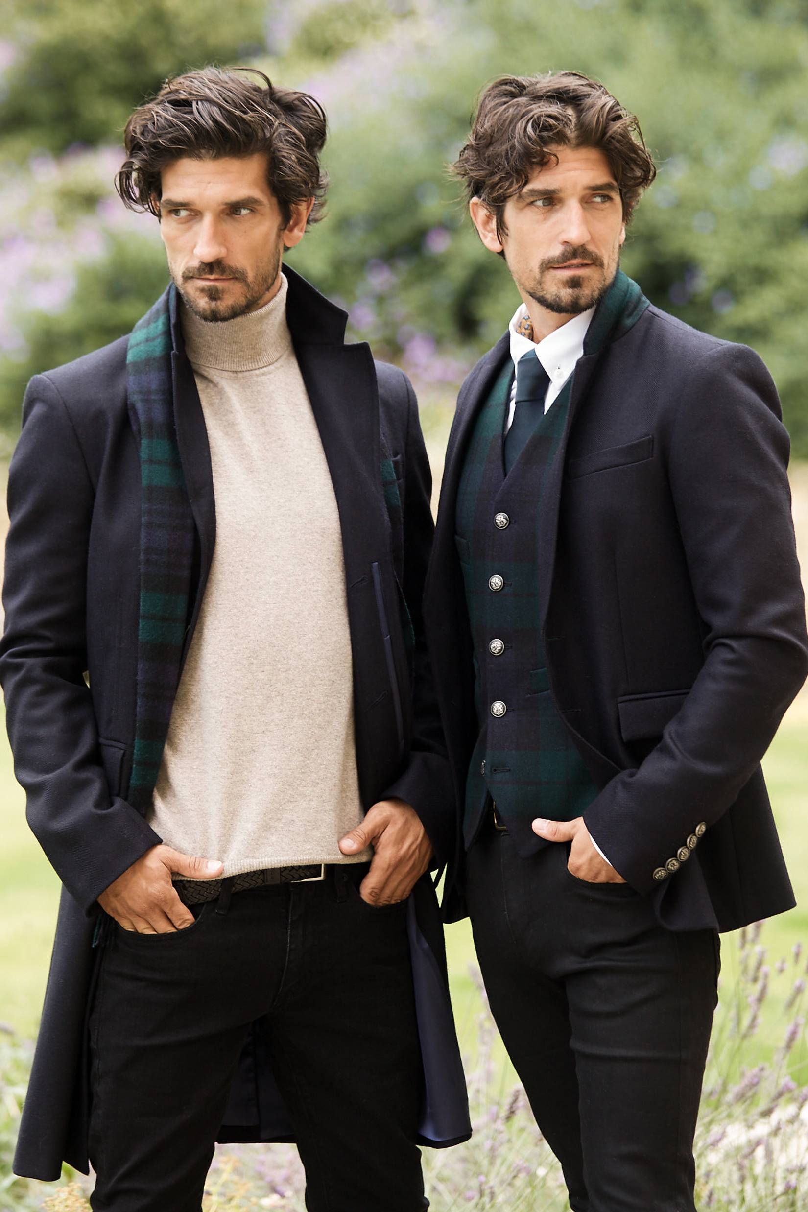 Two dark haired men stood side by side wearing navy coat and blazer with blackwatch scarf and waist coat