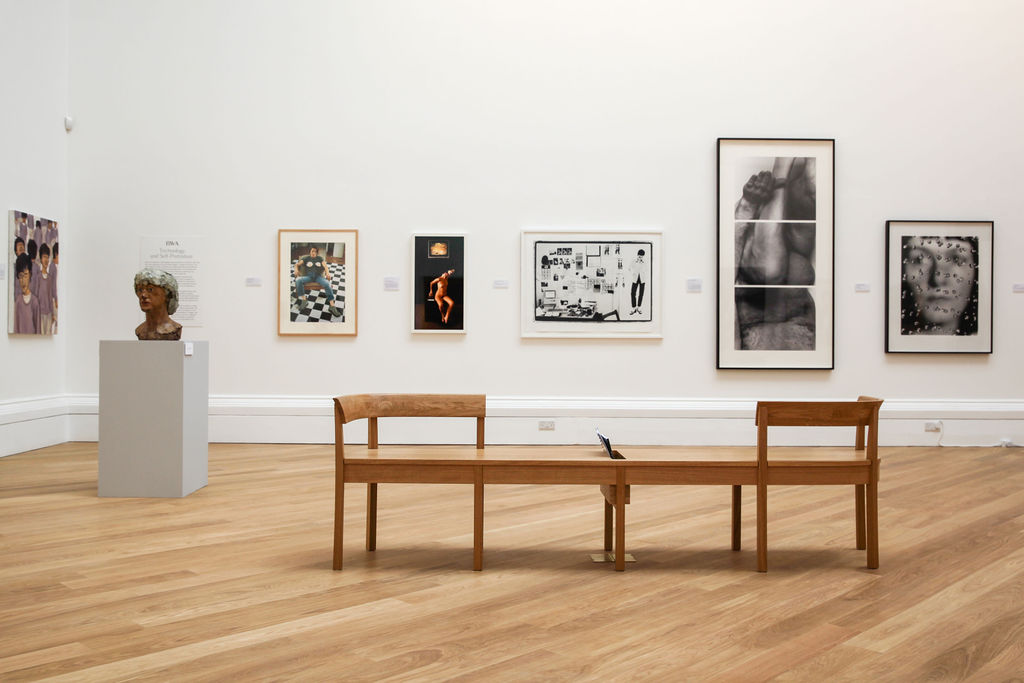 The RWA gallery space showing art with an oak bench in the foreground 
