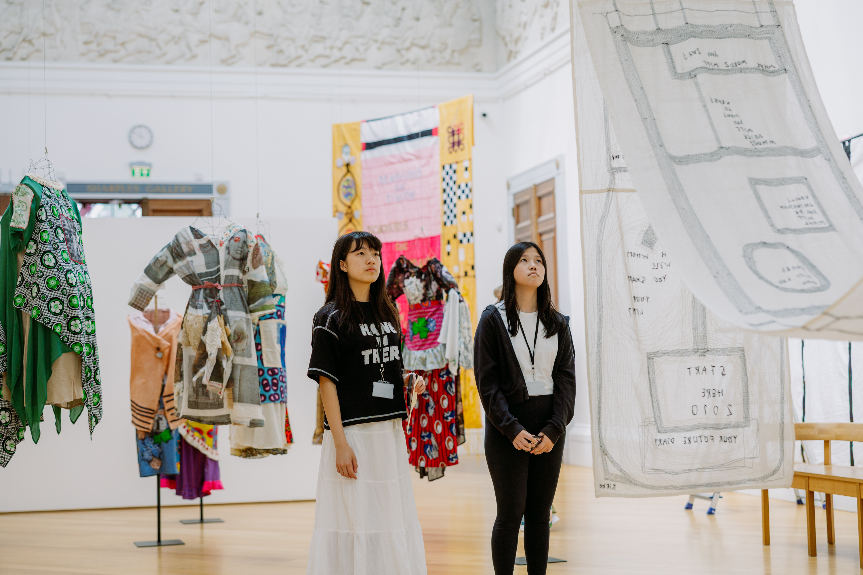 Two young students in the gallery looking up at an artwork during the Soft Power exhibition 