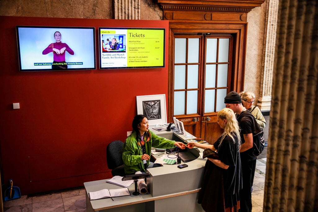 The welcome desk is positioned to the right as you enter the building, there are two screens displaying ticket prices, whats on and a British Sign Language introduction to the RWA 