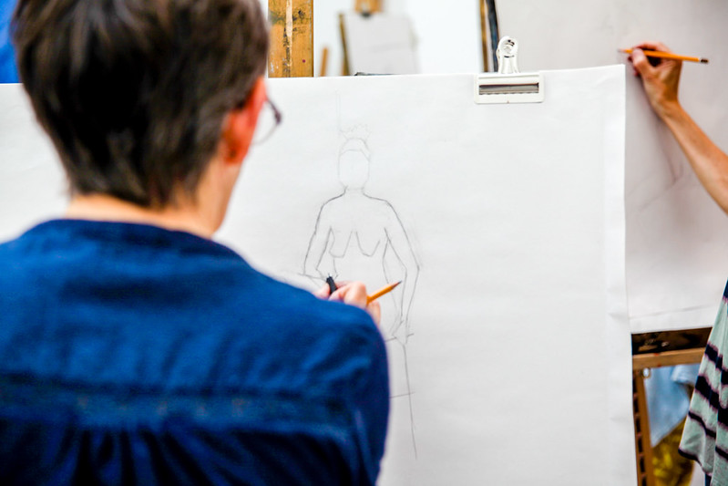 An image of a student drawing a life model with pencil 
