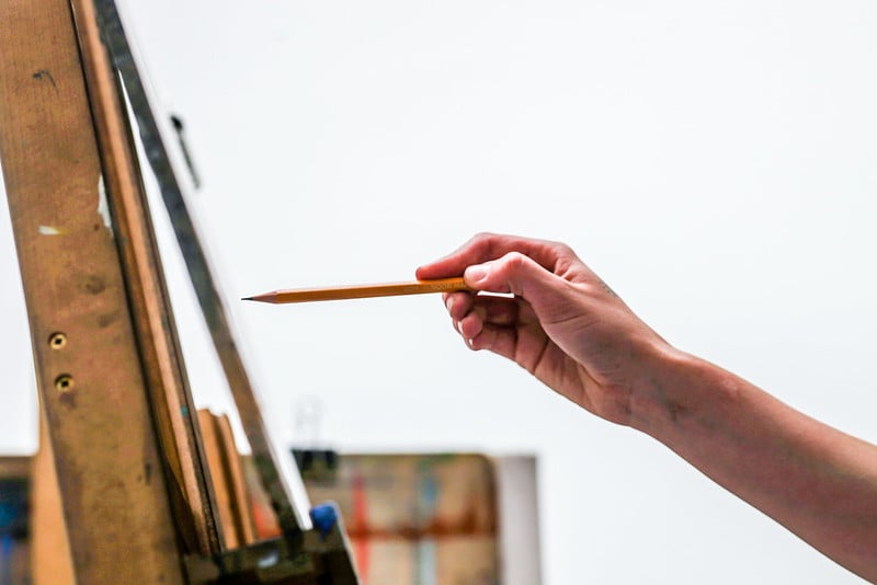 An image of a person holding a pencil up to an easel