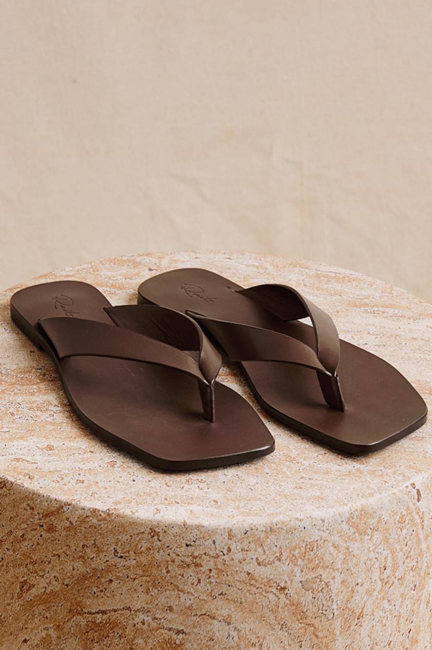 A pair of brown sandals displayed on a marble textured surface.