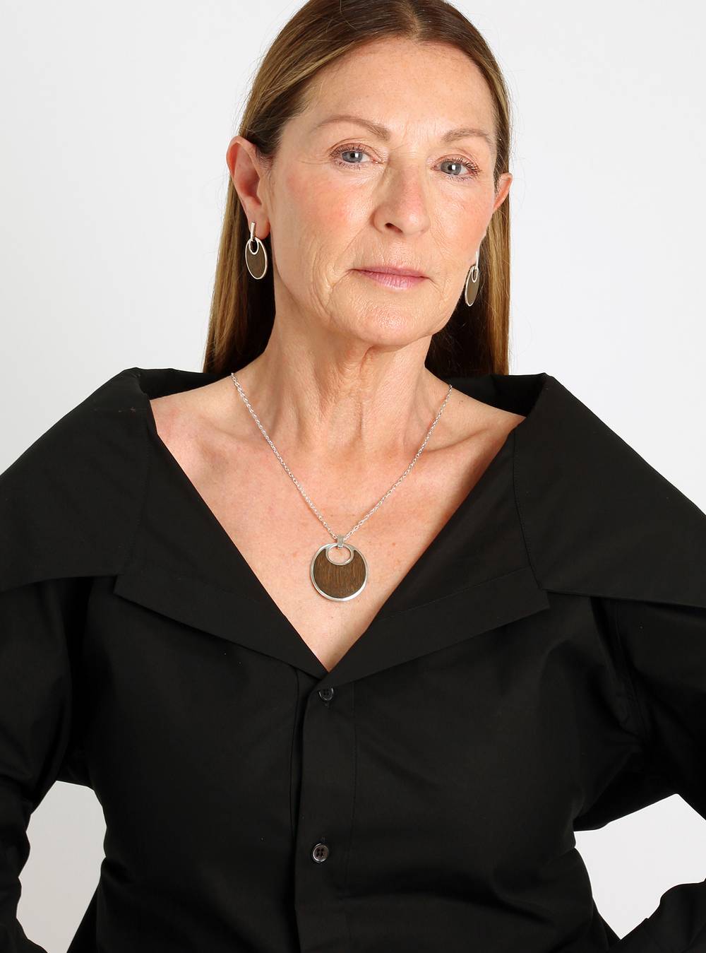 Woman wearing a silver and wood necklace with matching earrings