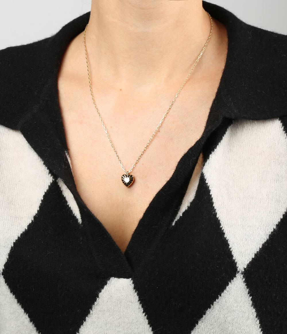 A woman with a black and white jumper is wearing a Heart silver pendant with a carved pattern on a silver chain