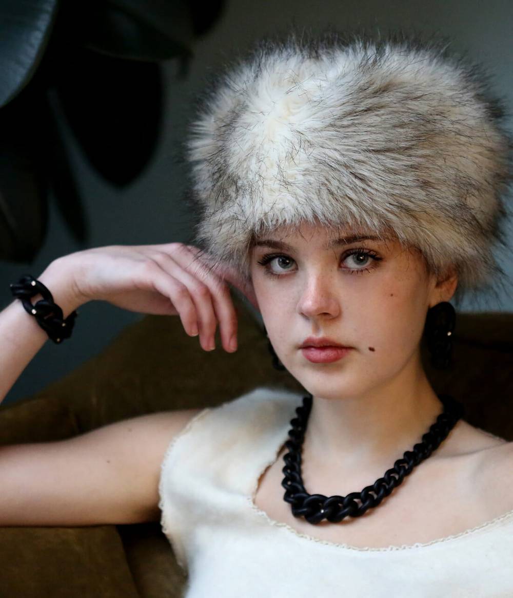 A girl is wearing the Raven necklace, earrings and bracelet which are made out of black caster seeds with six diamonds set on rose gold collets.