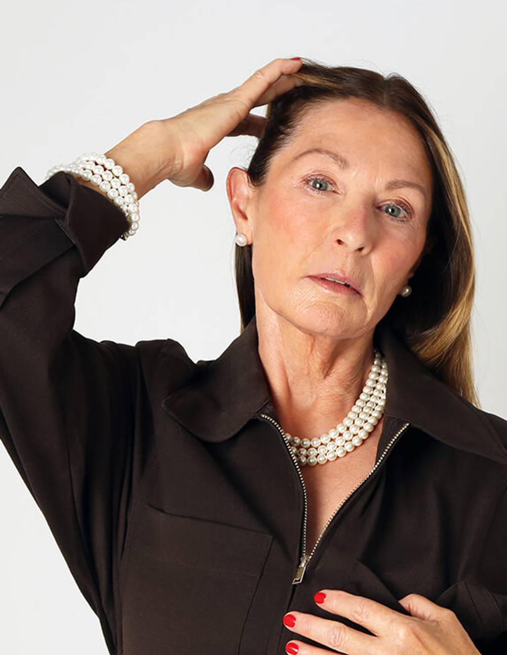 Woman wearing a three strand white pearl necklace and bracelet