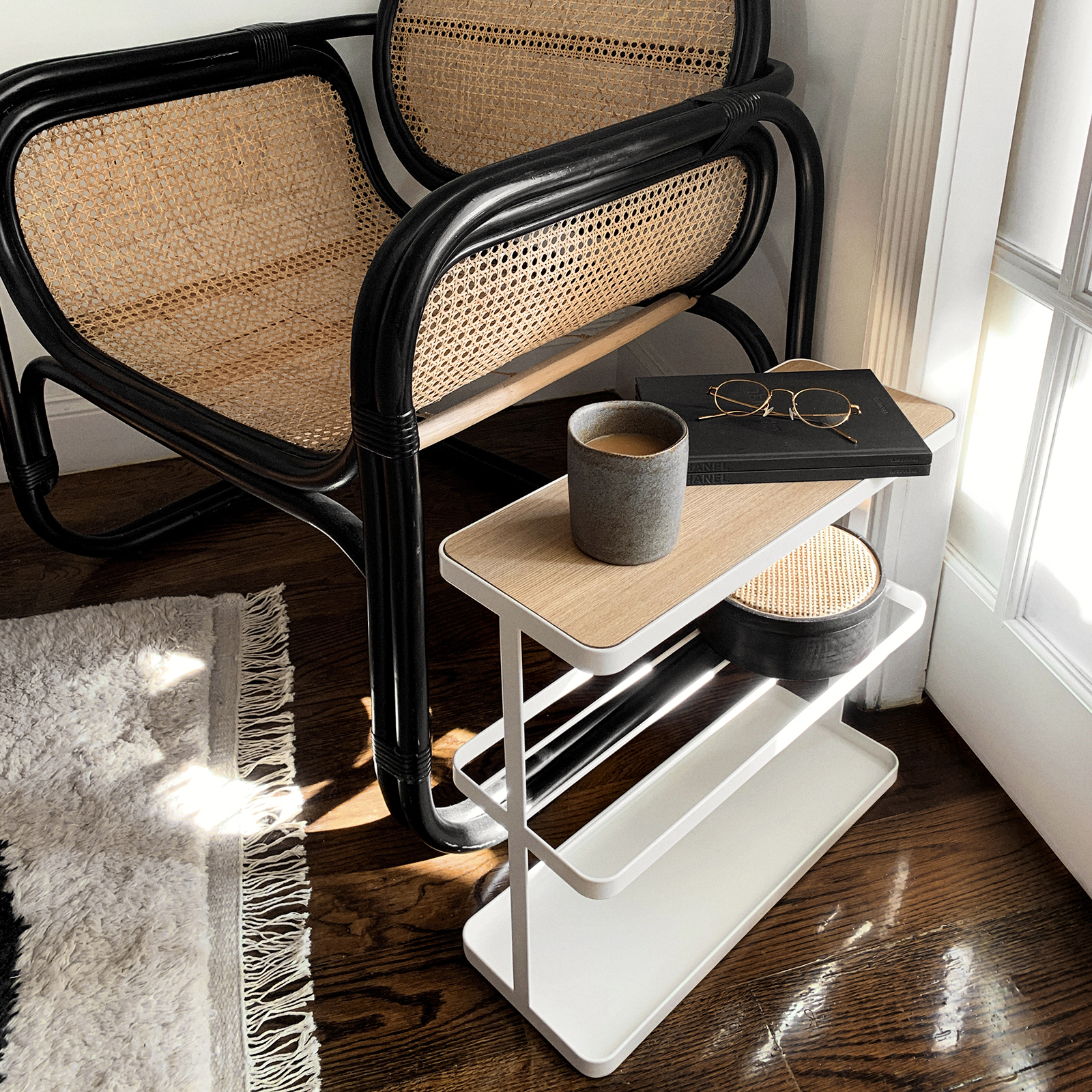 Yamazaki Home Tower Storage table on a notebook and a mug on the top, next to a chair. 