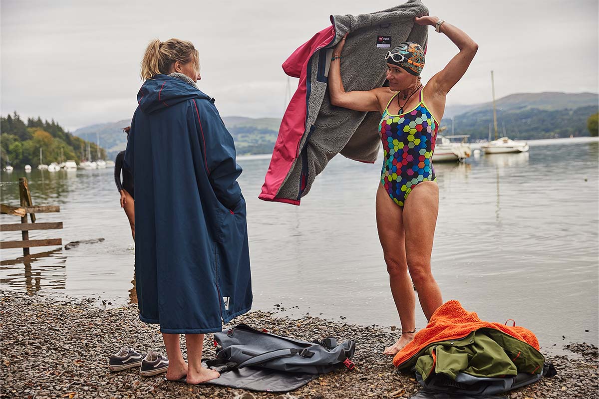 2 women with changing robes next to the shore of a lake