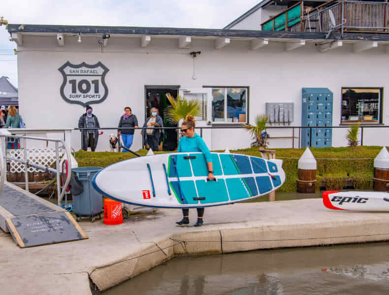 101 SUP organiser carrying a SUP surf board