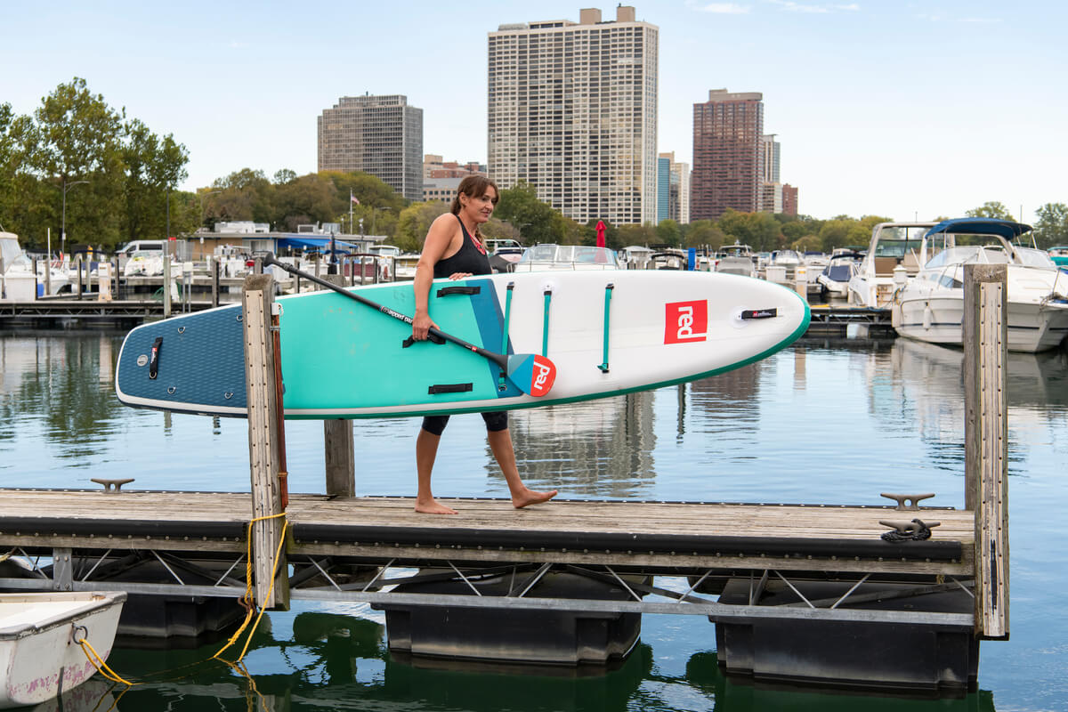 Woman Carrying Compact Paddle Board On a Jetty in Chicago