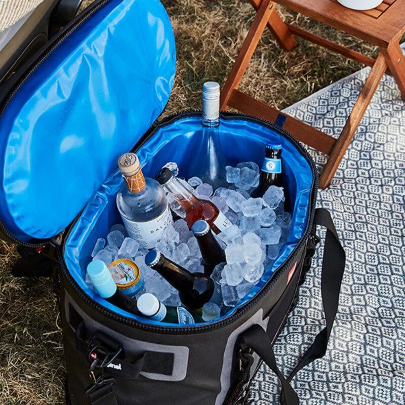 waterproof cooler bag filled with drinks and ice placed on a picnic rug