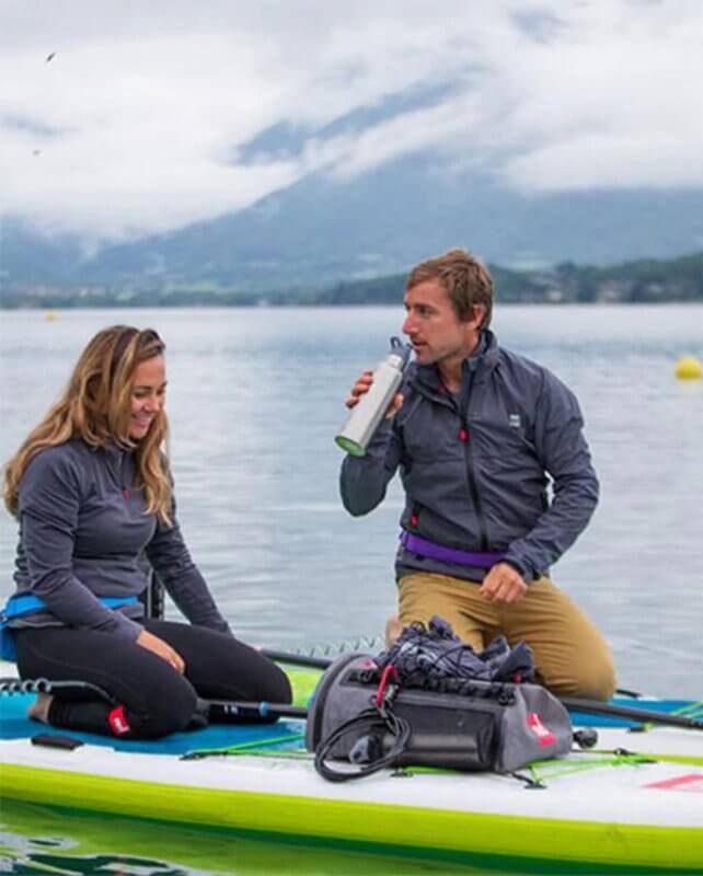 two people sitting on an inflatable paddle board with a sup deck bag attached