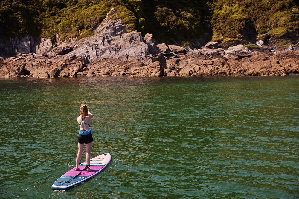 A woman on a lake paddling Touring SUP boards.