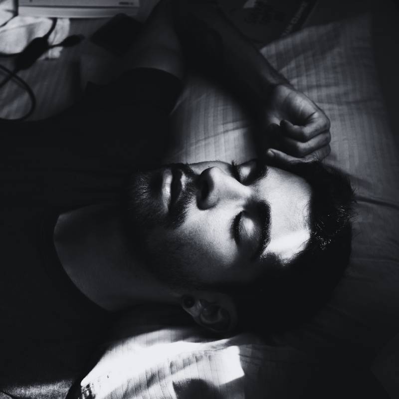 man with beard lying in the dark and sleeping