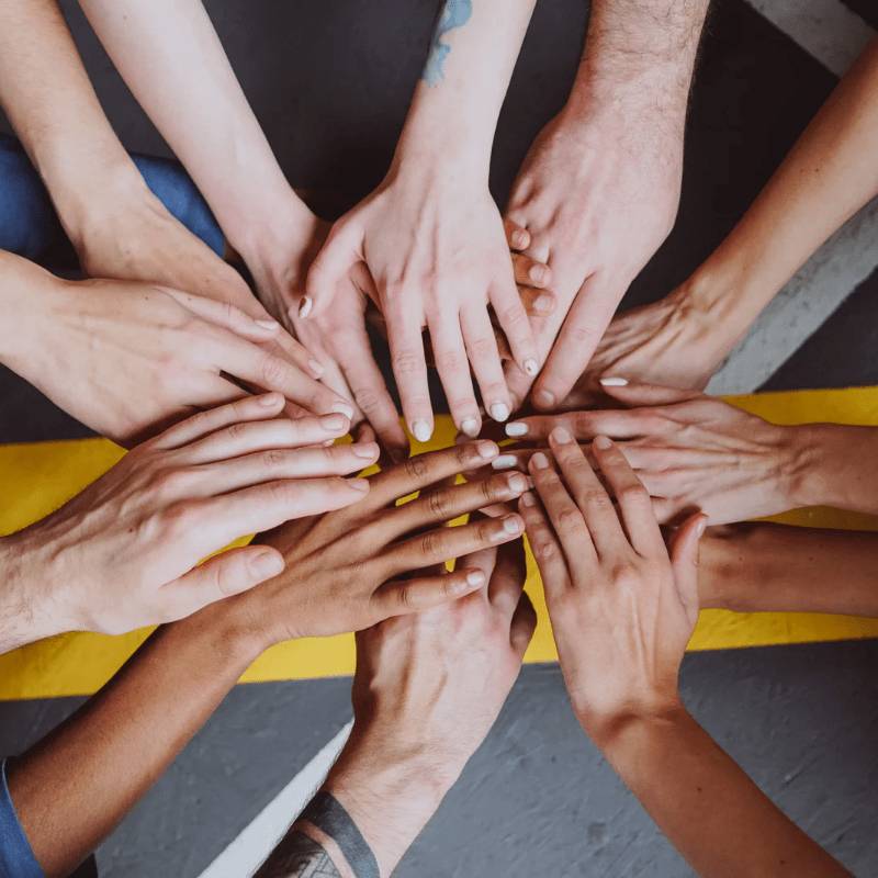 group of people all linking hands in a circle to show teamwork and community spirit