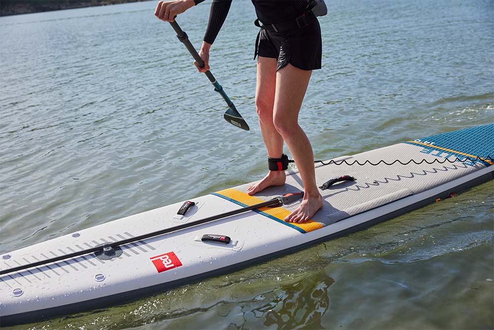 Woman standing on Red Original SUP using prime lightweight paddles
