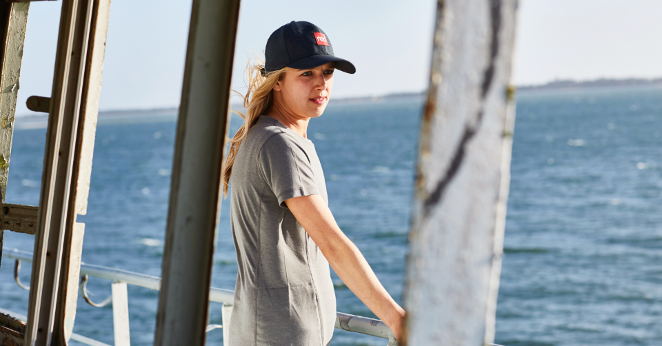 Woman looking out to sea wearing Red Original Paddle Cap and Performance T-shirt
