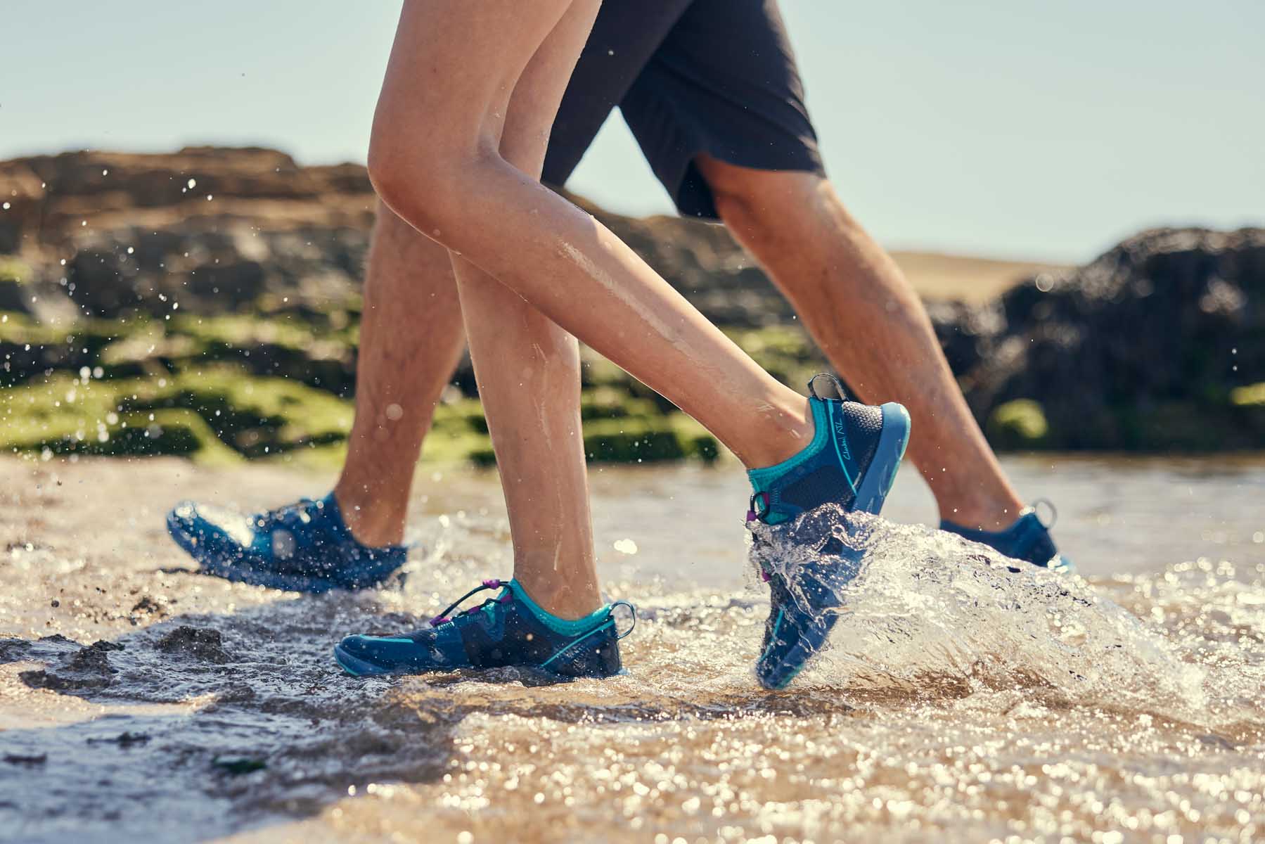 Two people walking on the beach wearing blue aqua shoes