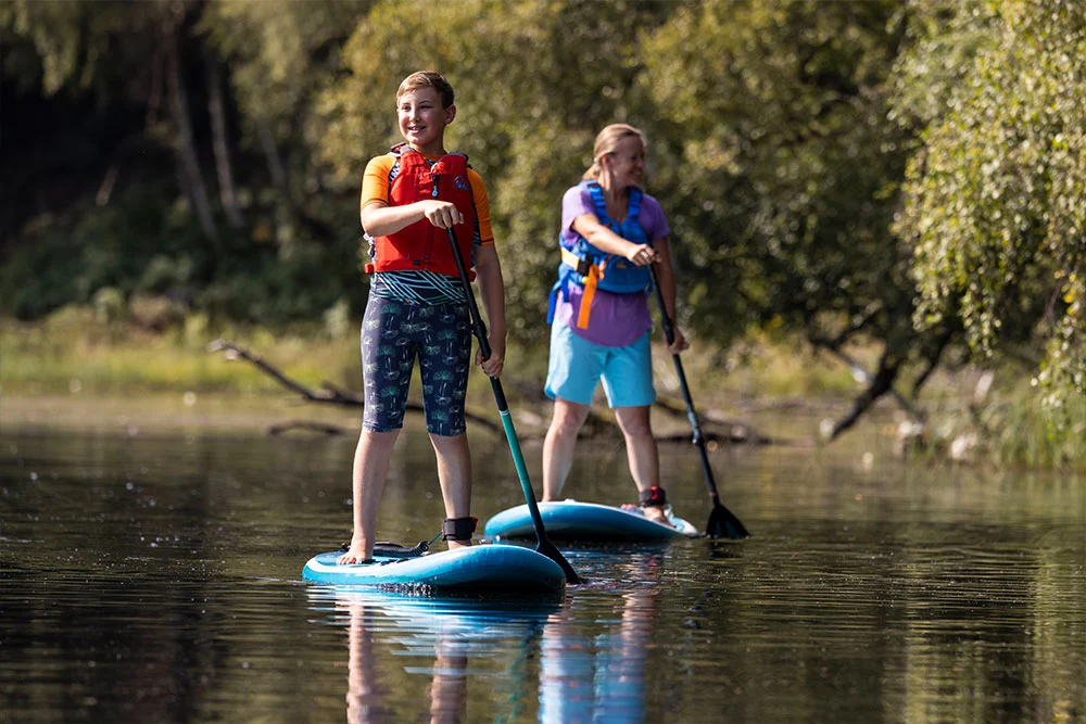 Adult and child paddle boarding in lake
