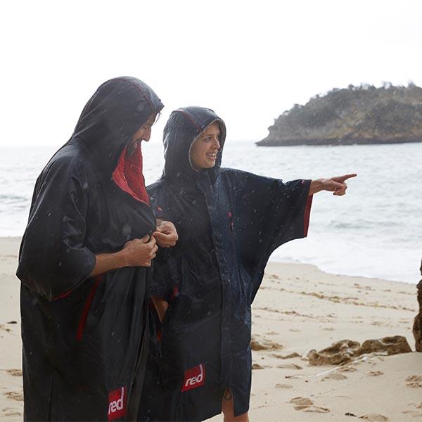 2 people in waterproof changing robes on a beach