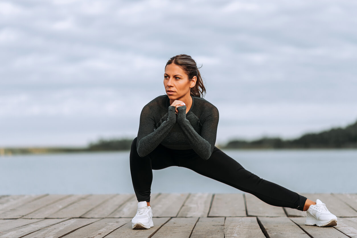 Front view of a fit woman doing side lunges near the river