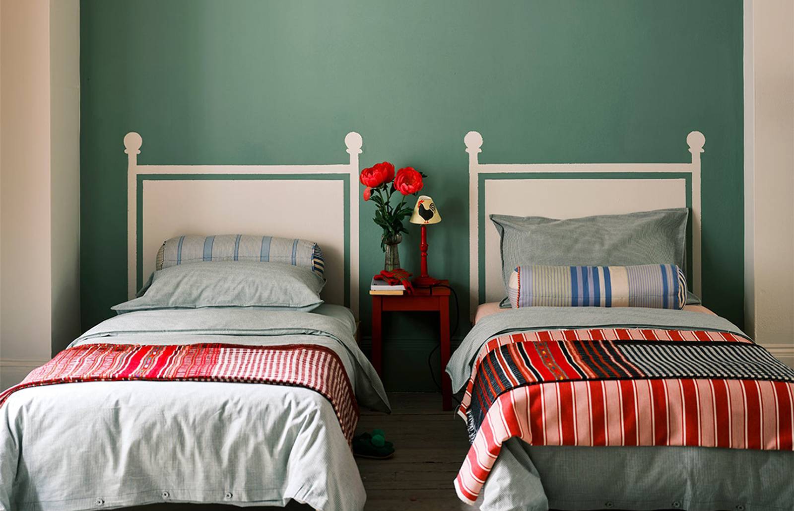 Green wall with two twin beds/Photography: Farrow & Ball/Breakfast Room Green walls, accompanied by Incarnadine ceiling stripes and School House White headboards, illustrate Farrow & Ball's color palette predictions for 2022.