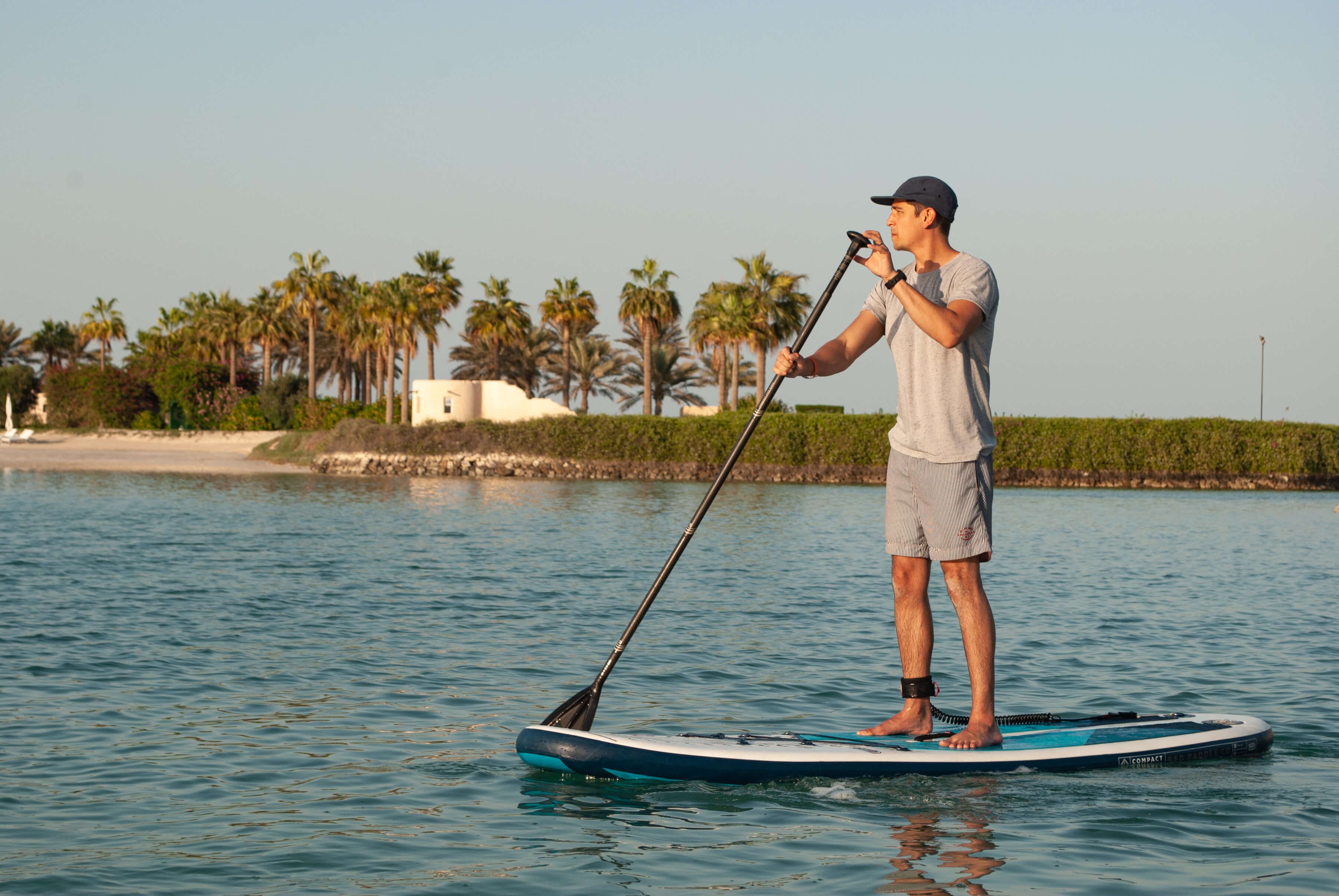 man paddle boarding in the sea with palm trees in the background