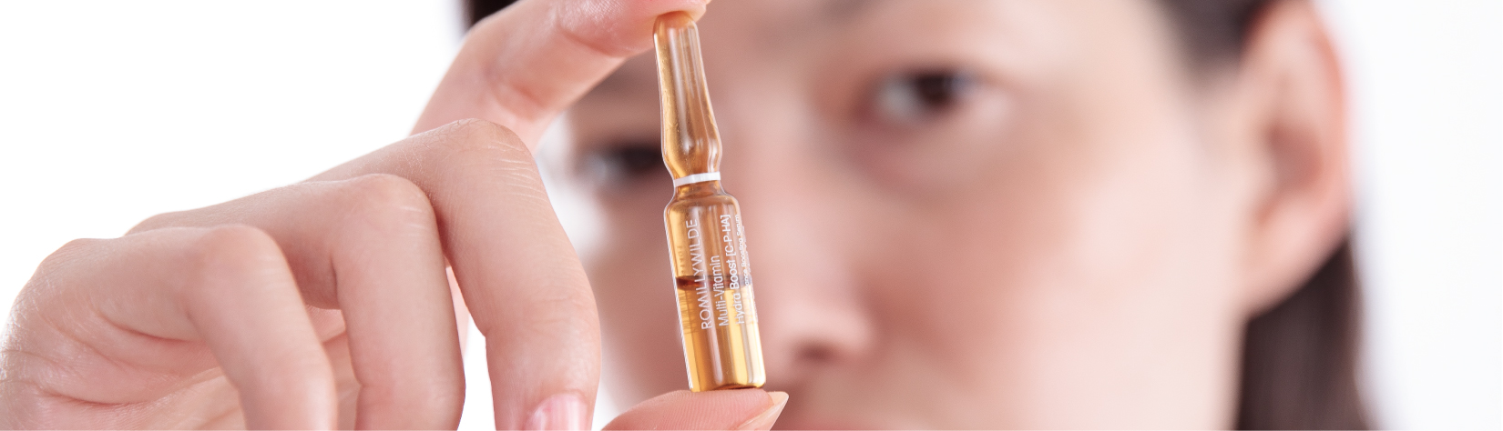 Woman Holding Skincare Ampoule Up In Front Of Her Face