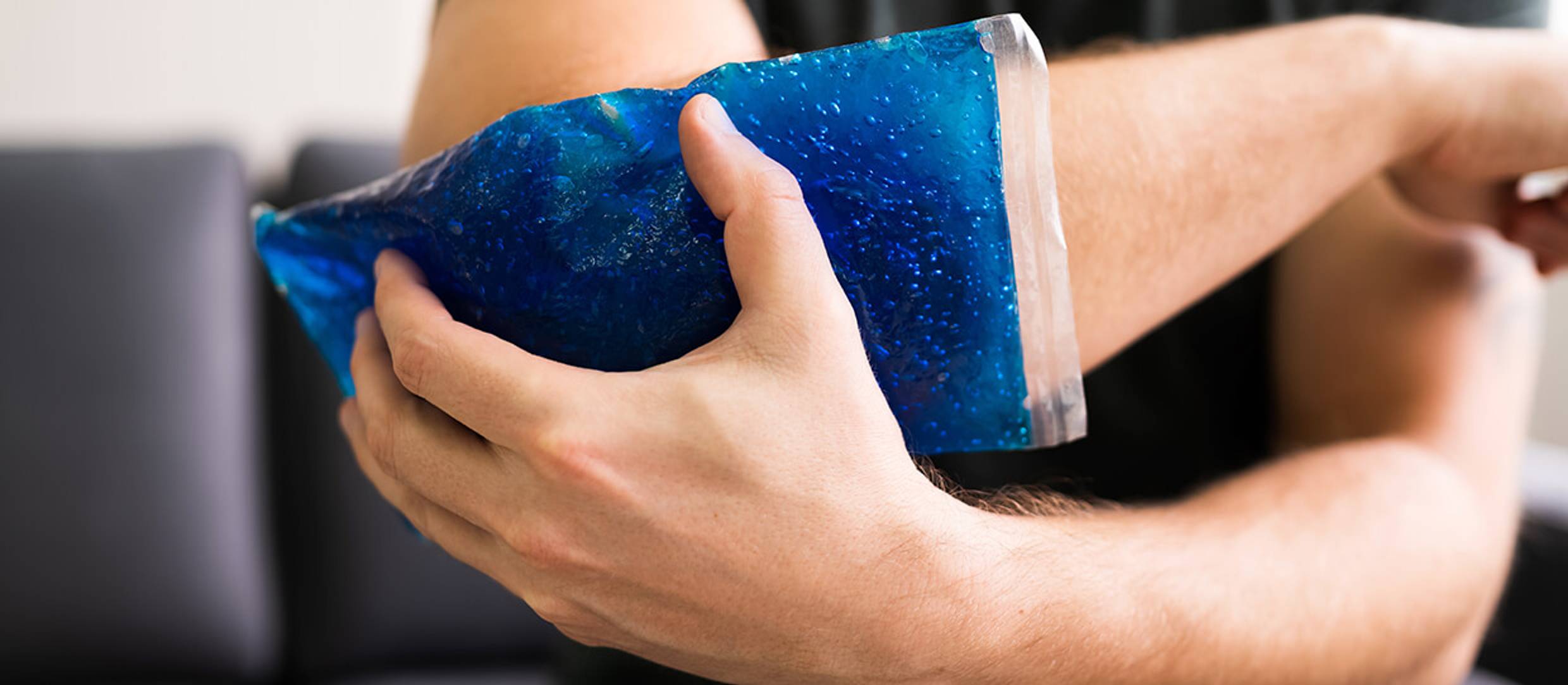 Man holding Cold Gel pack against his elbow for pain relief.