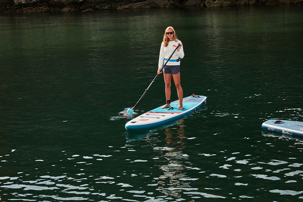A woman paddling using a touring paddle board
