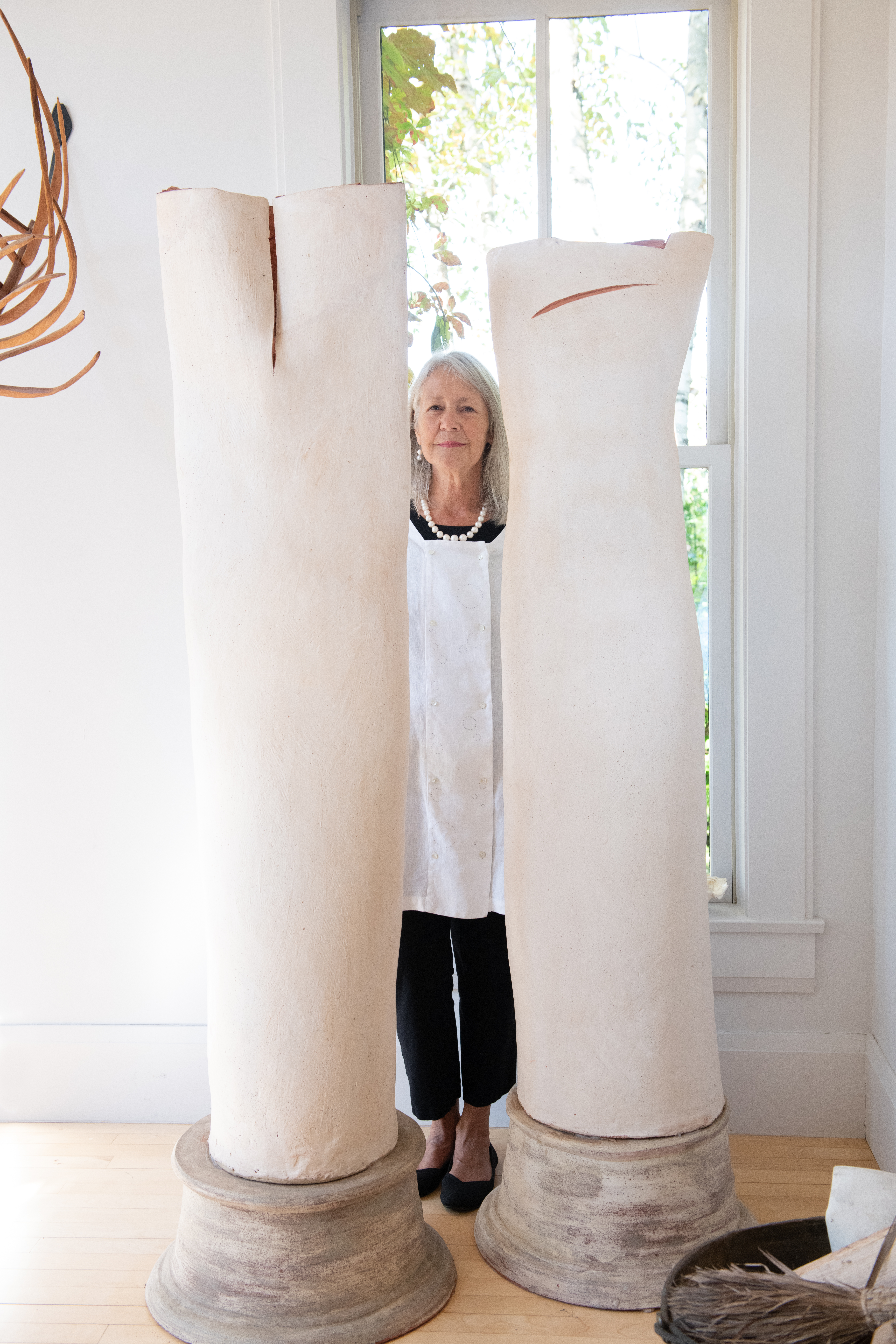 June in the white Medulla tunic, standing behind the ceramic “TreeForms” sculpture by Sharon Townshend