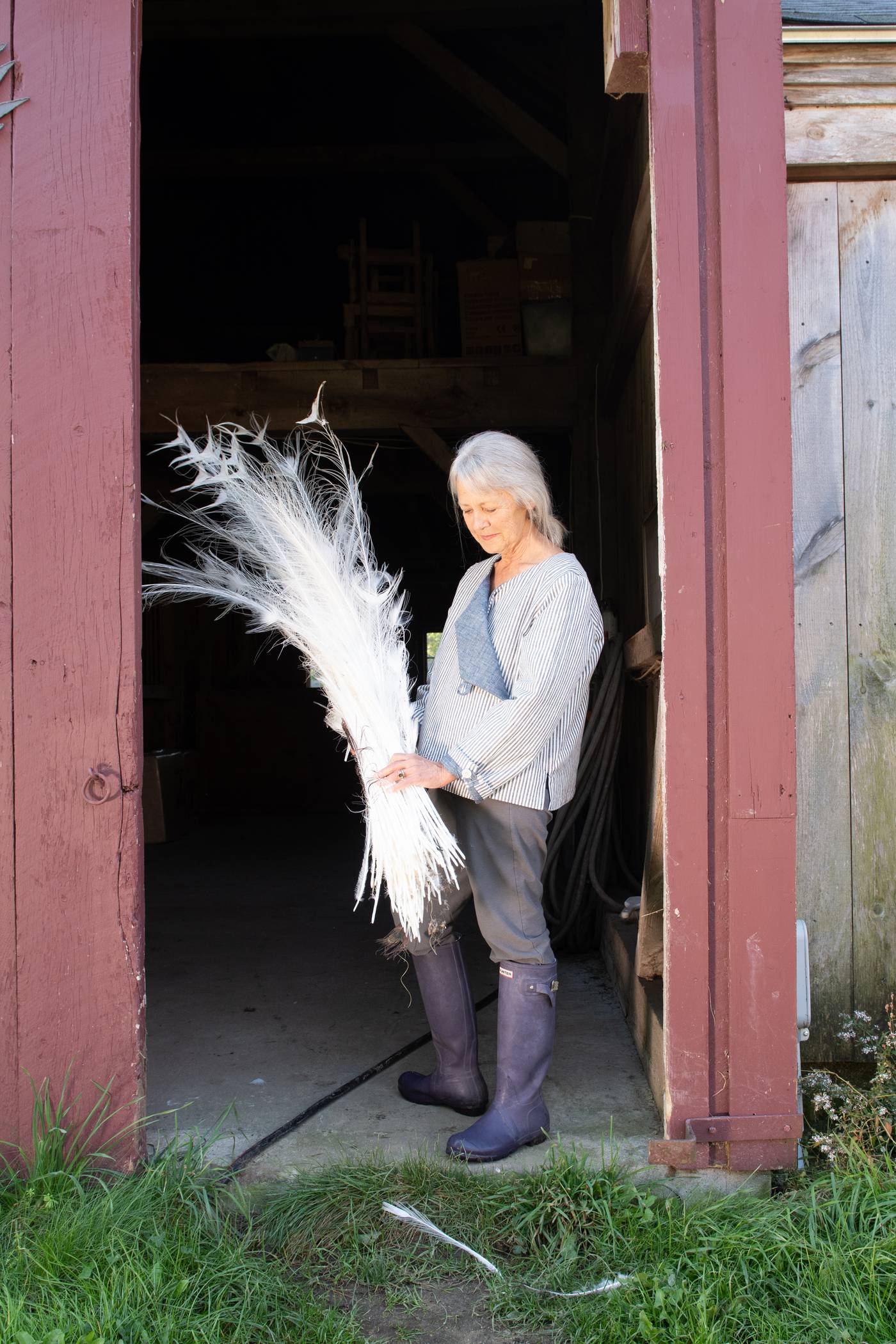 June, in the blue Latchkey jacket, holding white peacock feathers and looking down